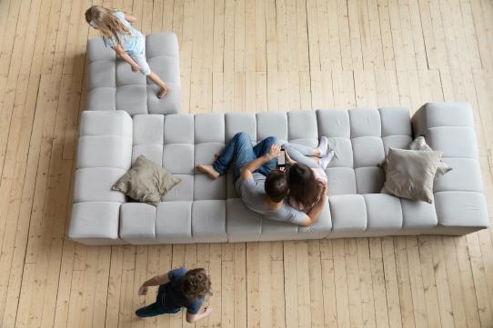 famiglia felice su divano con pavimento in parquet flottante riscladato con riscaldamento radiante elettrico a pavimento